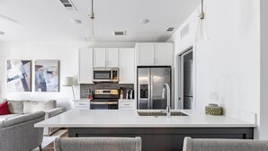 A modern kitchen with white cabinetry, stainless steel appliances, and a central island with seating.