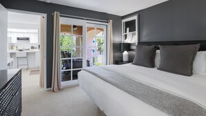 A modern hotel room with a large bed, a desk, and a sliding glass door leading to a balcony. - Keith Haring Inspired 2BD Deauville (Palm Springs)