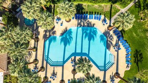 An aerial view of a swimming pool surrounded by palm trees and blue lounge chairs. - Keith Haring Inspired 2BD Deauville (Palm Springs)