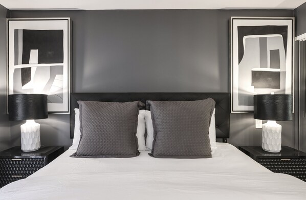 Une chambre d’hôtel moderne avec un grand lit, deux tables de chevet et des lampes fixées au mur.