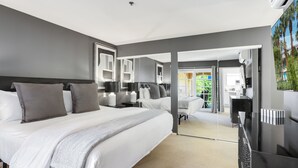 A modern hotel room with a large bed, a desk, and a mirror. - Keith Haring Inspired 2BD Deauville (Palm Springs)