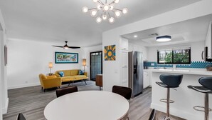A modern kitchen with a refrigerator, a dining area with a round table and chairs, and a yellow sofa in the living area. - Quaint & Serene in Mesquite CC (Palm Springs)