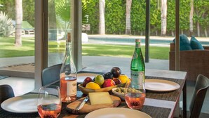 Una mesa servida con una botella de vino, un bol de fruta, una botella de agua y un plato de queso.