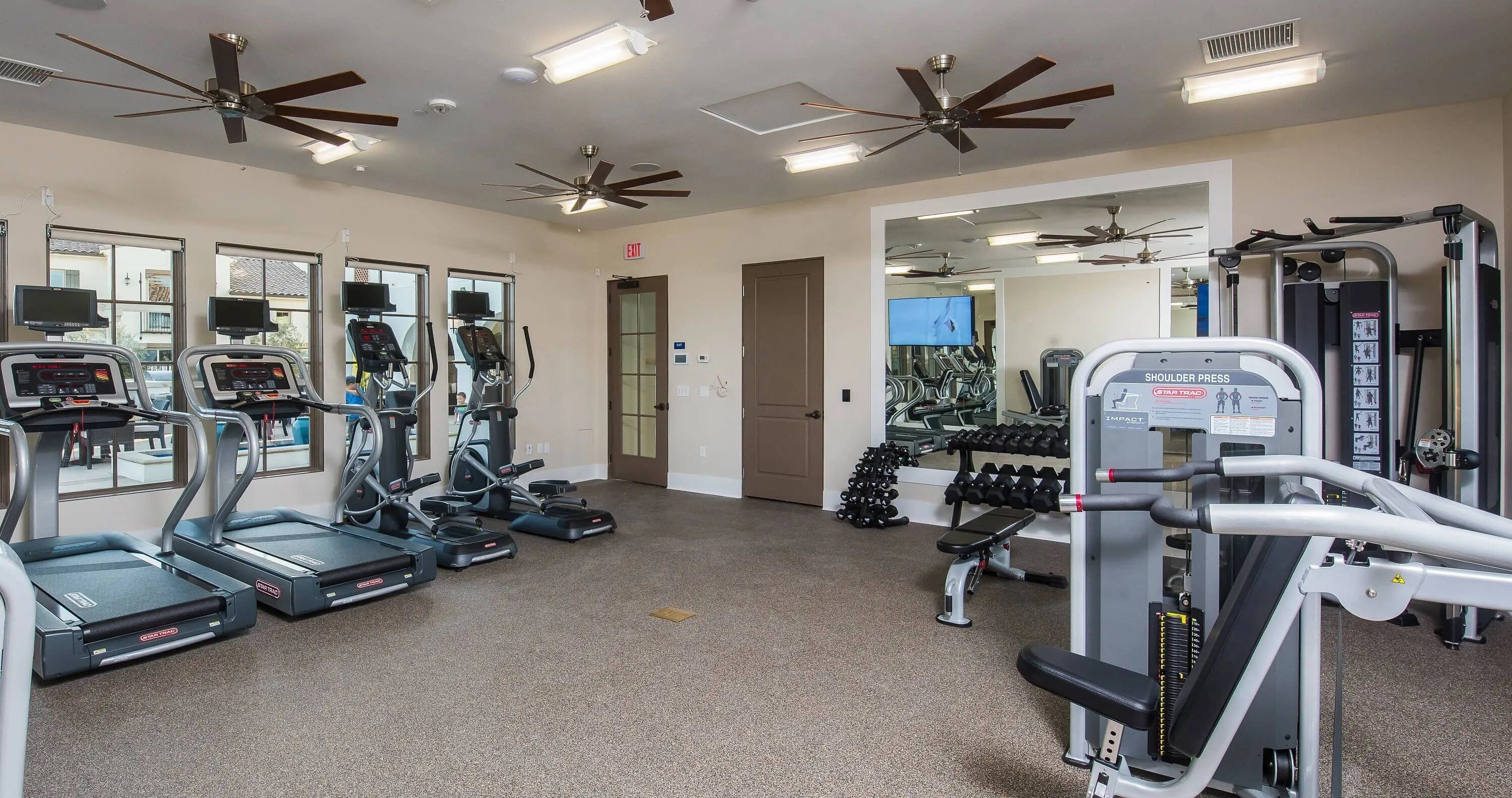 A gym with treadmills, elliptical machines, and weightlifting equipment.