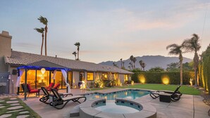 A residential property with a swimming pool, outdoor seating, and a well-lit patio area. - Casa San Marino (Palm Springs)