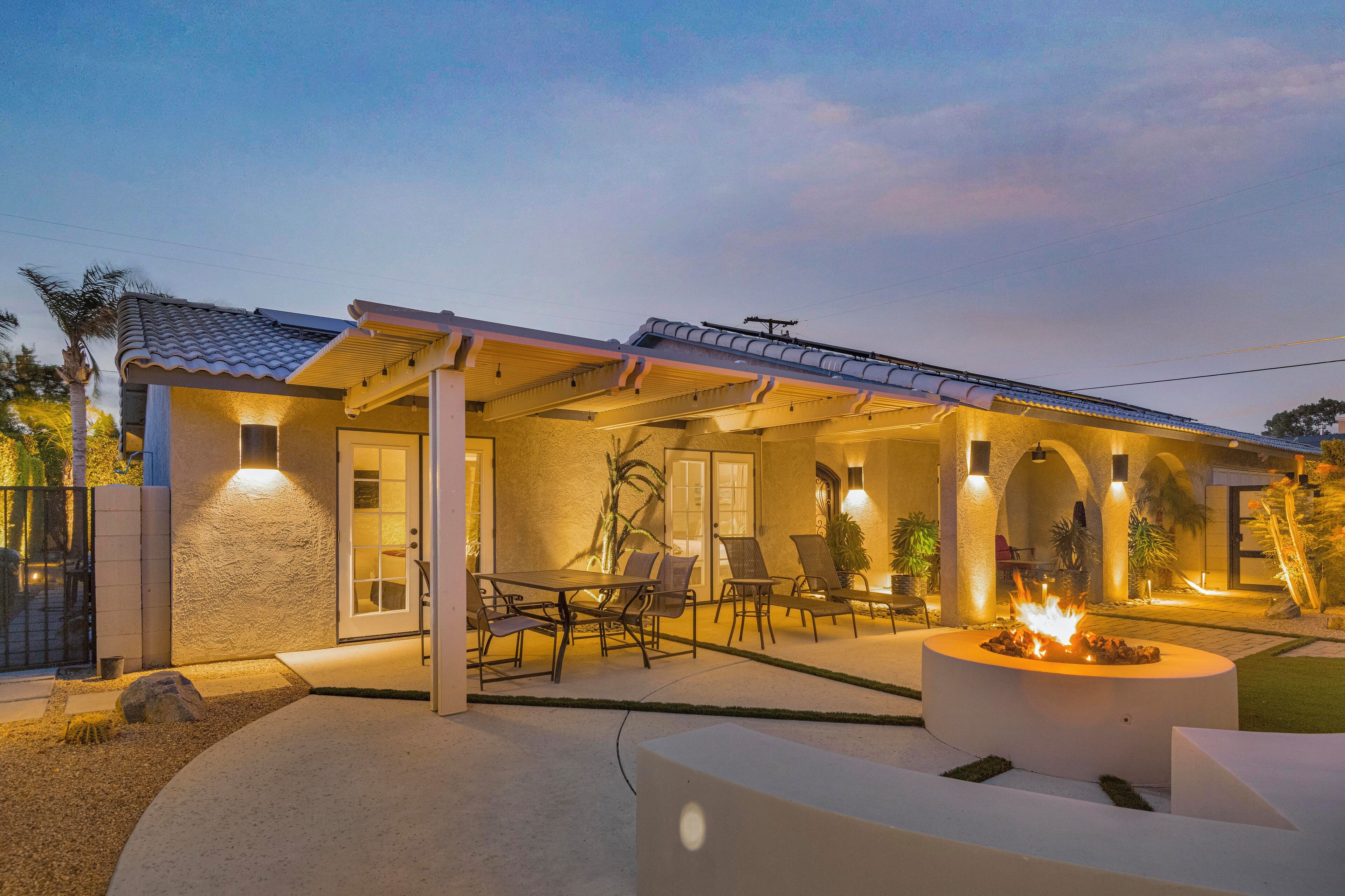 A modern house with a covered patio, outdoor seating, and a fire pit.