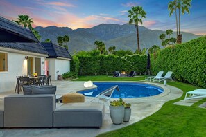 A pool area with a lounge chair, a dining table, and a sofa. - Arch House (Palm Springs)