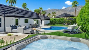 Ein modernes Haus mit Swimmingpool, Sitzgelegenheiten im Freien und Whirlpool.