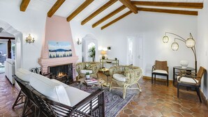 Un salon spacieux doté d’une cheminée, de meubles en osier et d’un sol en pierre.