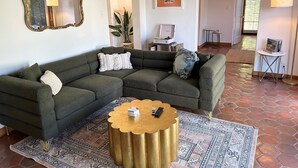 Un salon chaleureux avec un canapé d’angle, une table basse dorée et un tapis à motifs.