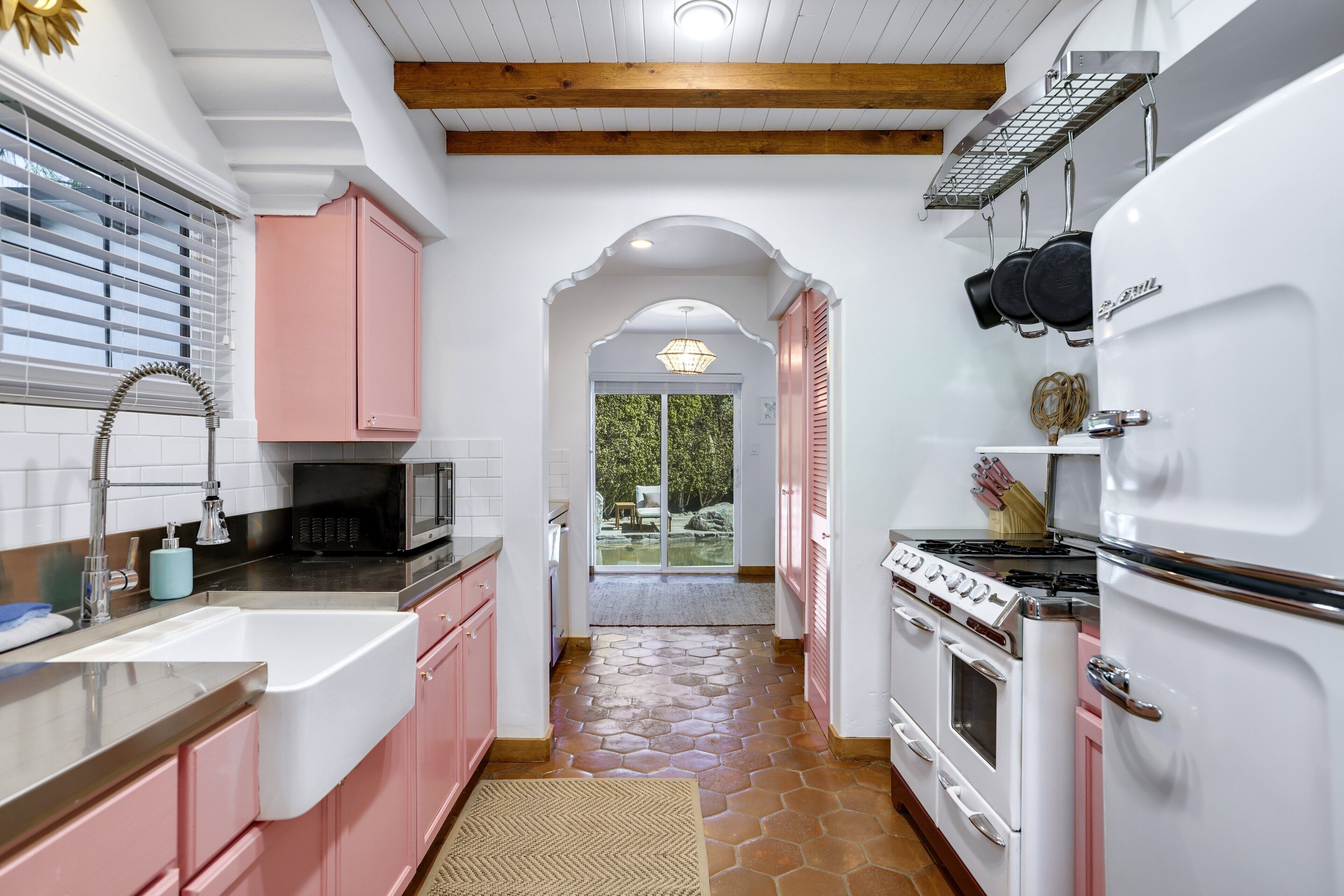 A kitchen with pink cabinets, a white refrigerator, and a stove.