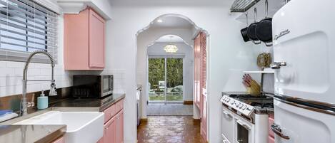 A kitchen with pink cabinets, a white refrigerator, and a stove.