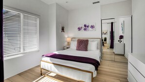 A modern bedroom with a bed, a nightstand, a mirror, and artwork on the wall. - Flora Vista Sunshine (Palm Springs)