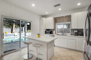 A modern kitchen with a central island, a built-in microwave, and a refrigerator. - Flora Vista Sunshine (Palm Springs)