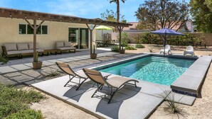 Un jardin avec une piscine, des meubles de patio et une pergola.