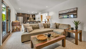 Een moderne woonkamer met een bank, salontafel en een schilderij van een berglandschap.