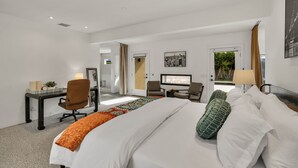 Hotelkamer met een groot bed, bureau, twee stoelen, televisie en raam met uitzicht op groen.