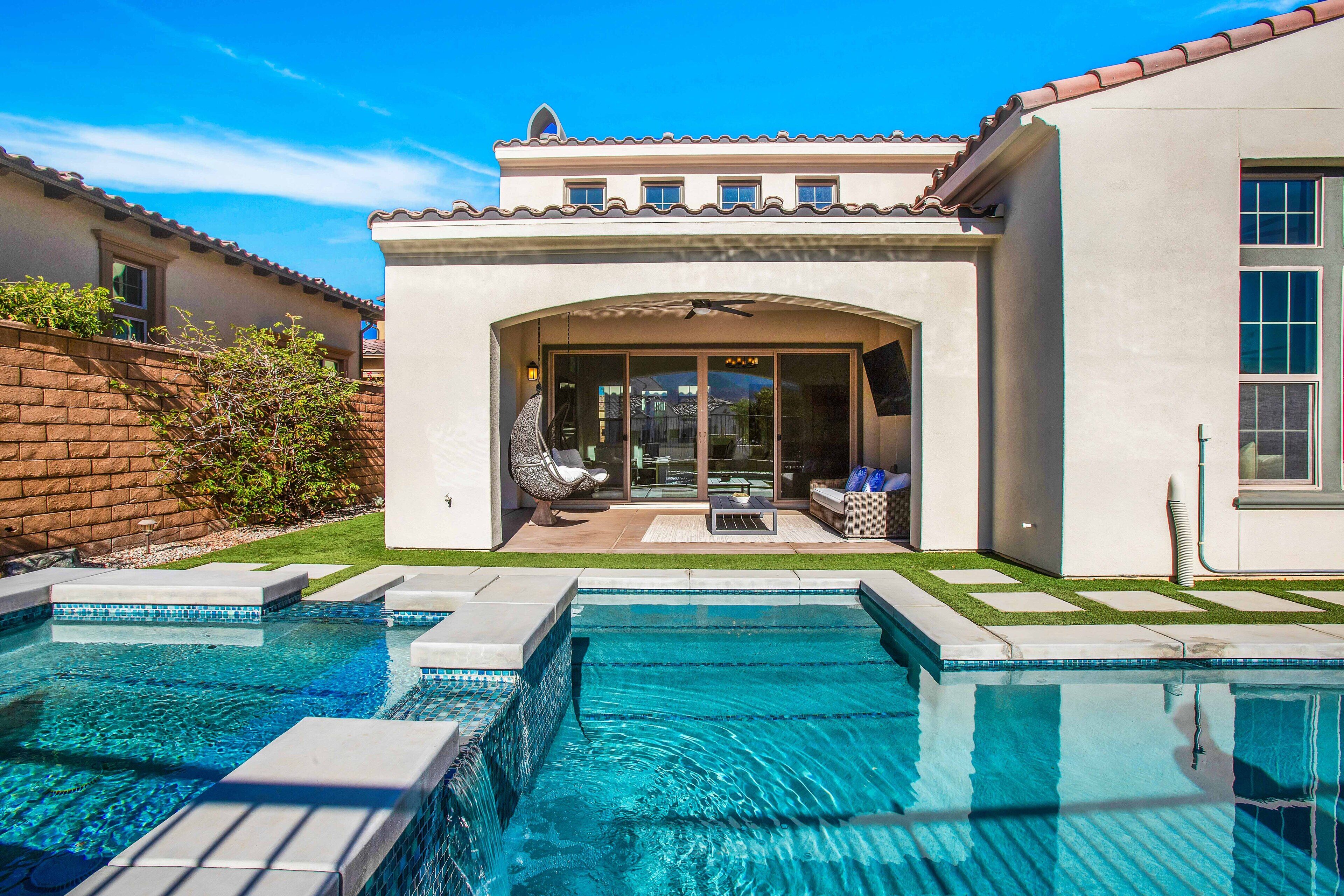 Una casa moderna con piscina, mobiliario de patio y una zona de estar al aire libre techada.