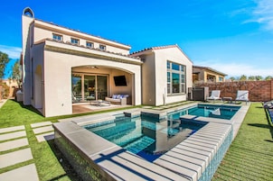 Una casa moderna con piscina, mobiliario de patio y un césped bien cuidado.