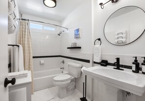A modern bathroom with a bathtub, toilet, and sink. - Stylish Boho Treasure (Palm Springs)