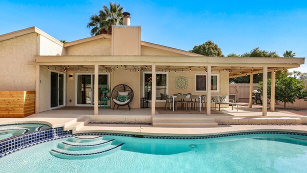 Ein Haus mit Swimmingpool, Außenbereich und einer Pergola.