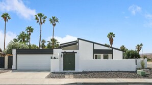 A modern two-story house with a white exterior, a green door, and a garage. - Desert Green Serenity (Palm Springs)