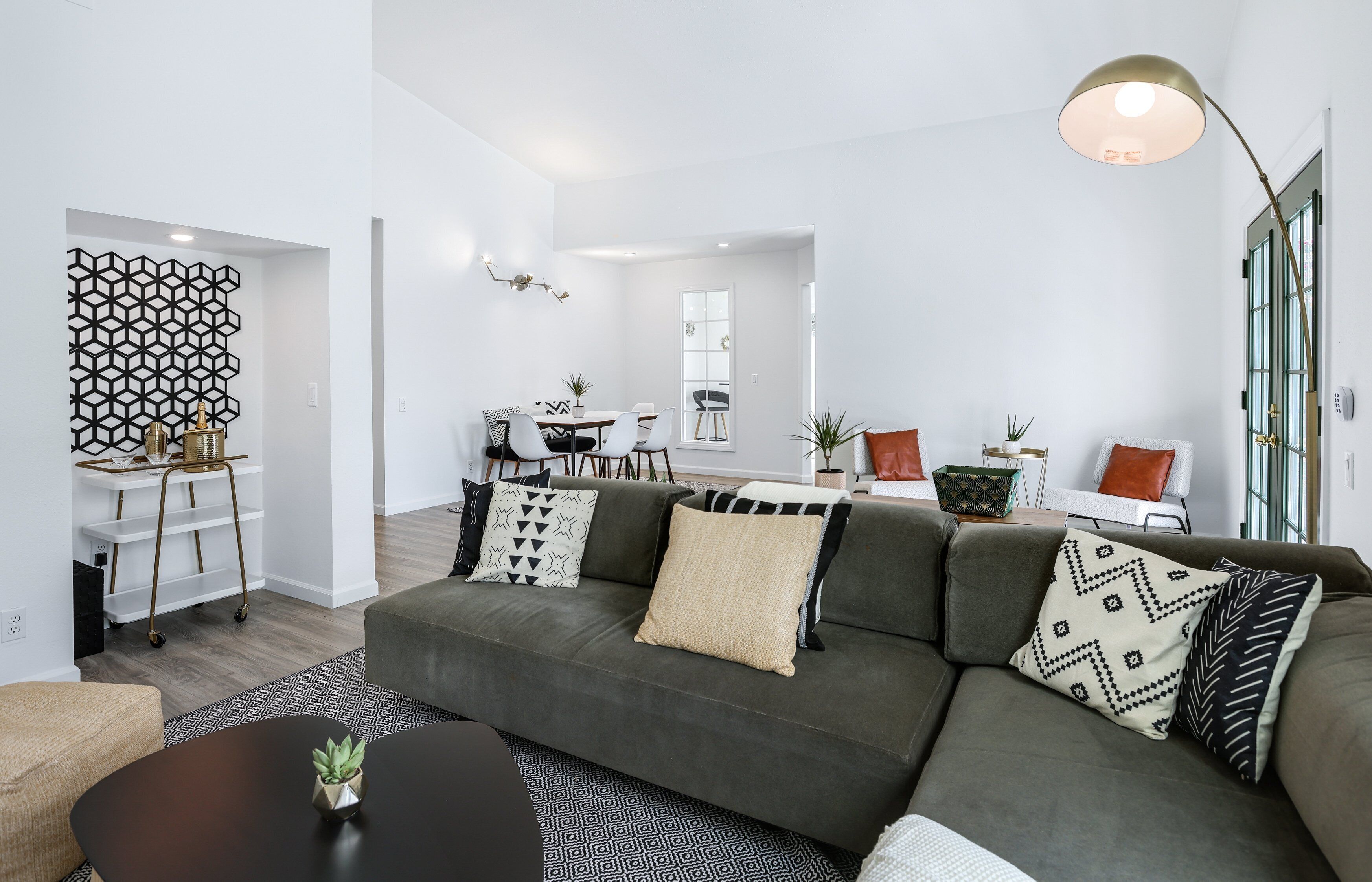 A modern living room with a sectional sofa, a coffee table, and a dining area with a table and chairs.