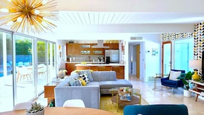 A modern living room with a sofa, coffee table, and a dining area with a table and chairs. - Serenity in Sunmor (Palm Springs)