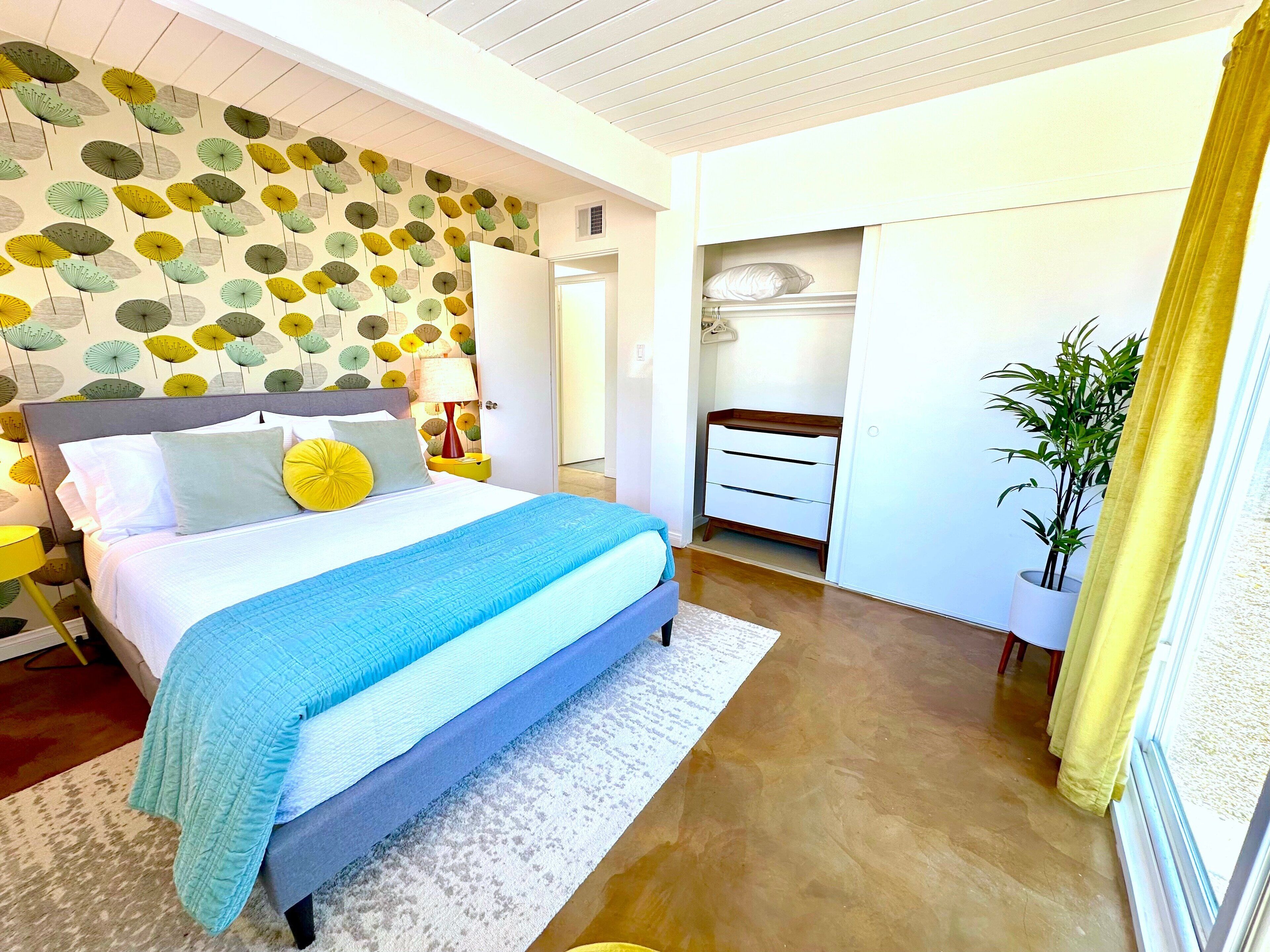 A bedroom with a bed, bedside tables, a wardrobe, and a potted plant.