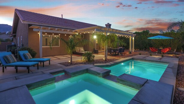 A modern house with a swimming pool, outdoor seating, and string lights.
