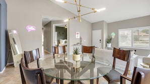 A modern dining area with a glass table, wooden chairs, and a central plant.