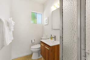 A bathroom with a toilet, sink, and mirror. - Bright & Harmonious Oasis (Palm Springs)