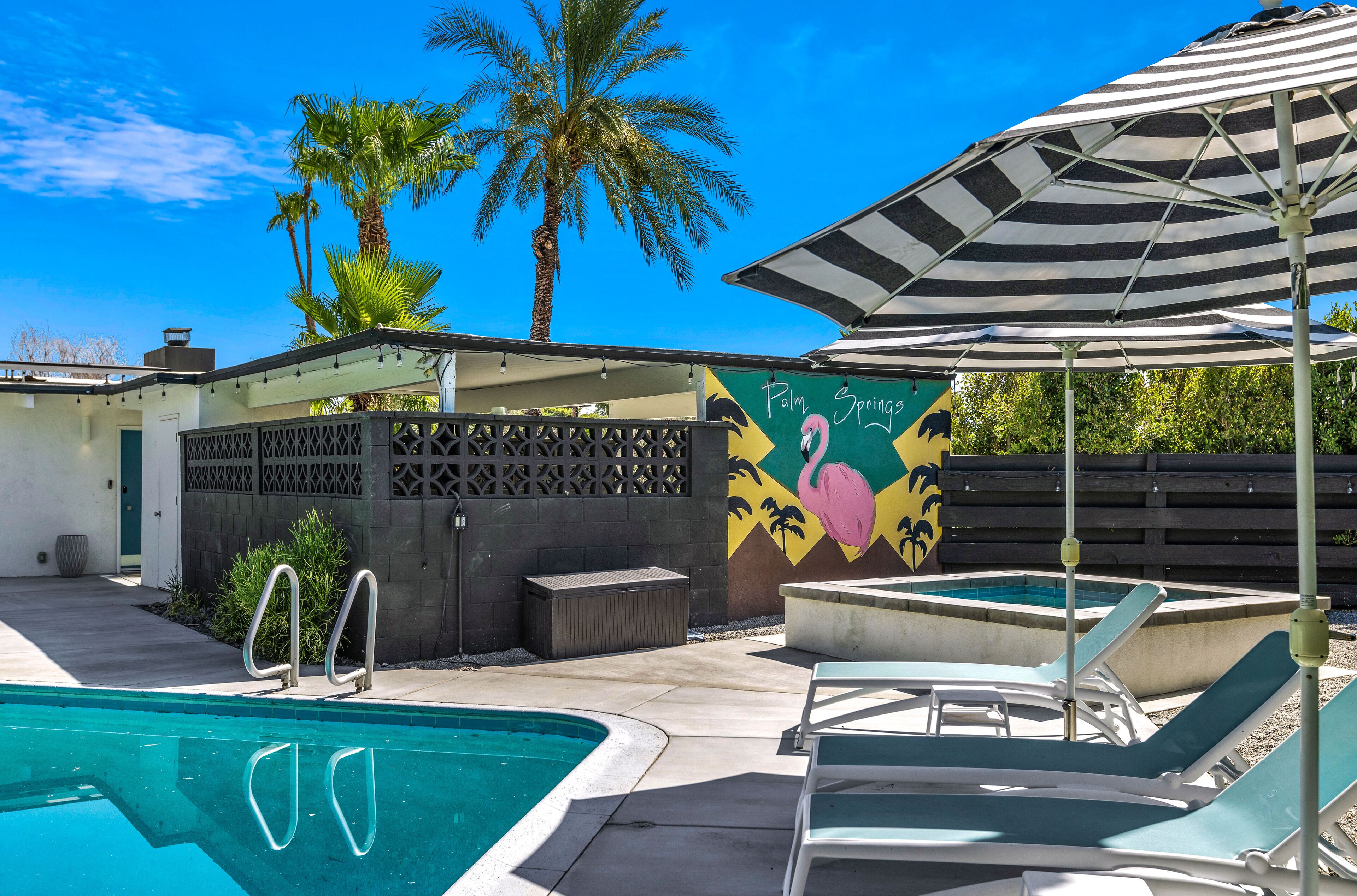A swimming pool with lounge chairs and a striped umbrella.