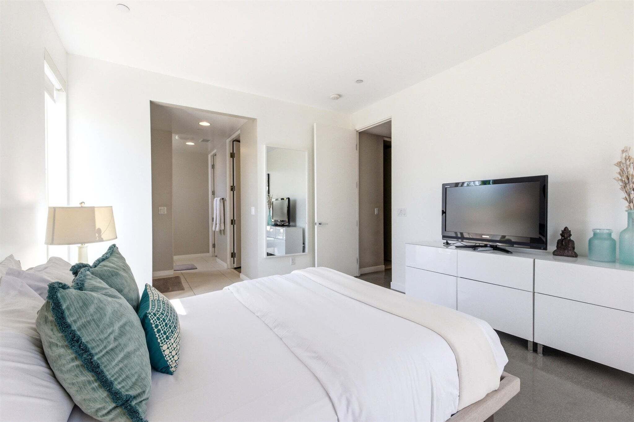 A modern bedroom with a bed, a TV, and a walk-in closet.