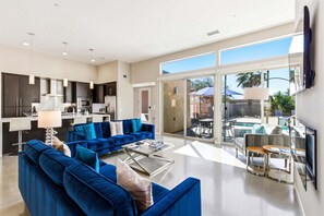 A modern living room with a blue sofa, a coffee table, and a TV. - Modern Desert Lux (Palm Springs)