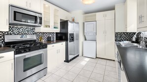 Une cuisine moderne dotée d’appareils électroménagers en acier inoxydable, de meubles blancs et d’un revêtement mural en carreaux.