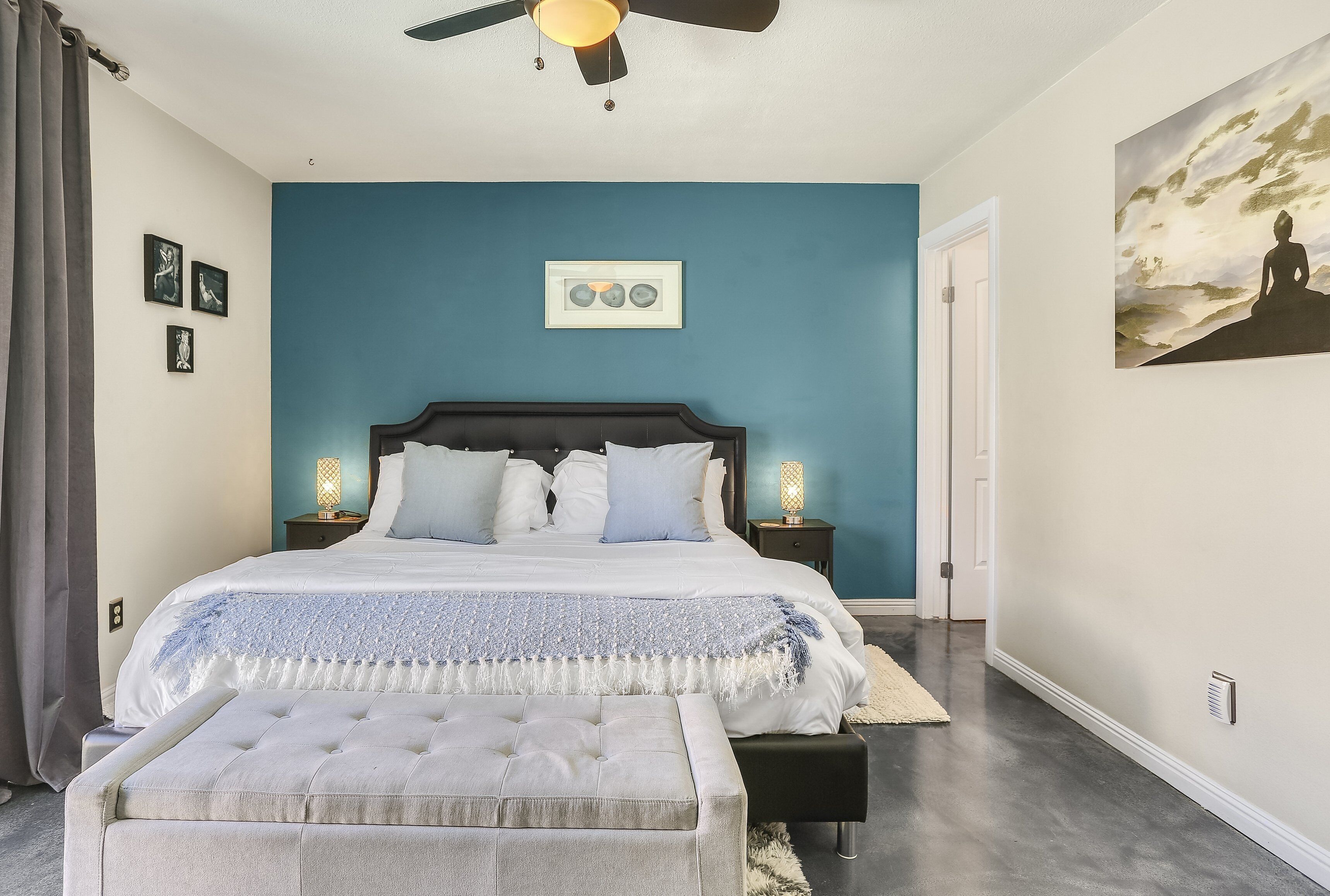 Un dormitorio con cama, lámparas de noche, ventilador de techo e iluminación en la pared.