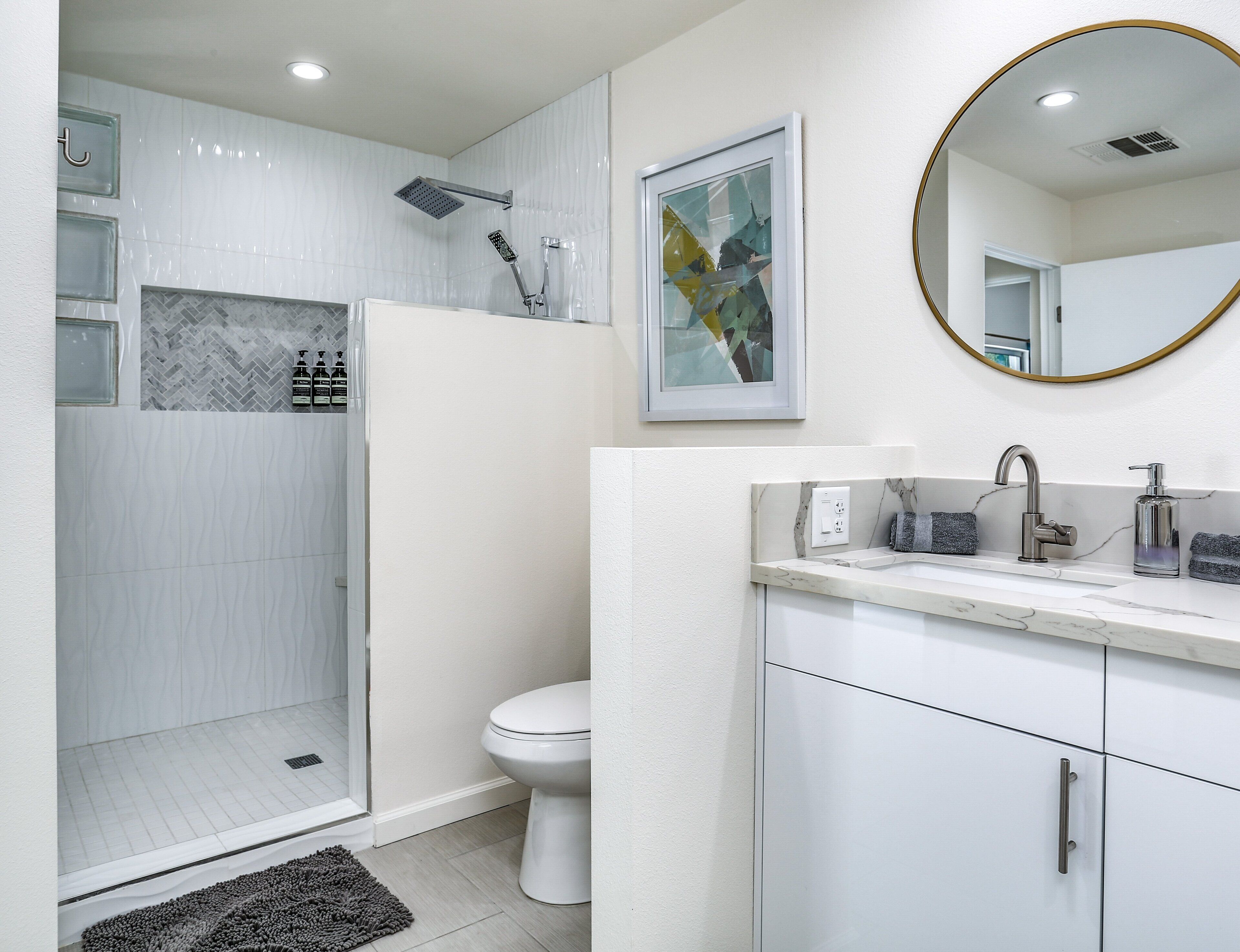 A modern bathroom with a shower, toilet, and sink.
