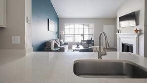 Een moderne keuken met een roestvrijstalen spoelbak, een zithoek met een bank en tafel, en een open haard.
