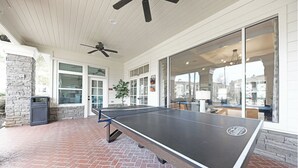 A ping pong table in an outdoor area with a brick floor, a ceiling fan, and large windows. - Landing | Amazing 1BD, Courtyard, Game Room (Murfreesboro)