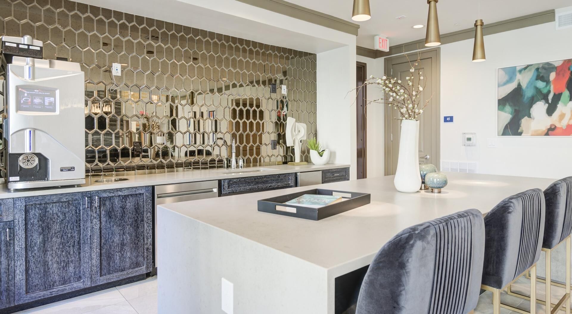 A modern kitchen with a central island, a coffee machine, and a decorative hexagonal wall.