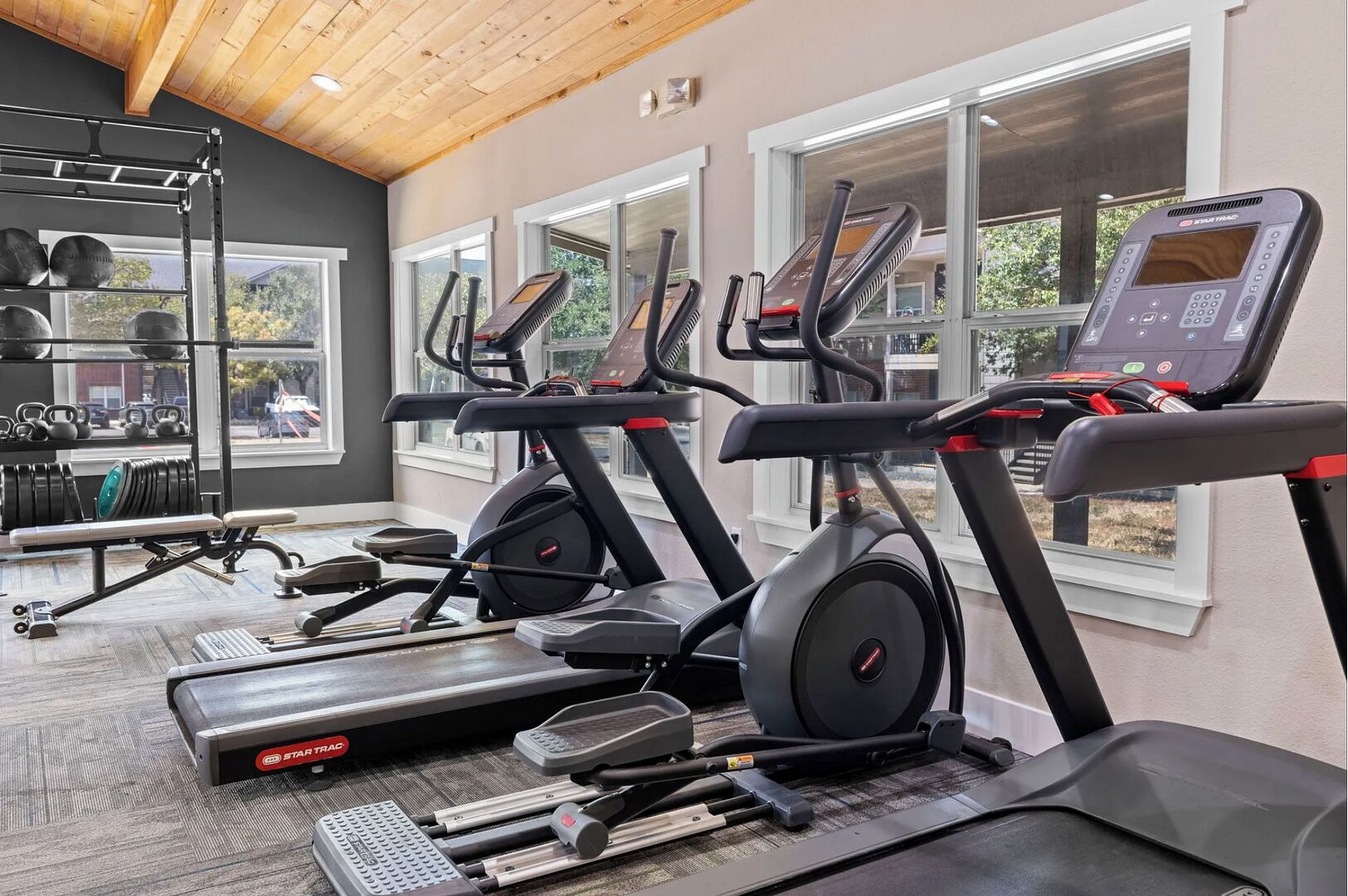 Une salle de sport équipée de tapis de course, d’appareils de musculation et d’un support à poids.