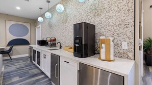 A modern kitchen with a coffee machine, a microwave, and a coffee dispenser.
