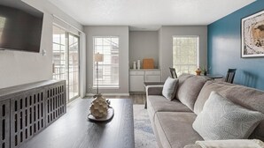 Un salon moderne avec un canapé gris, une table basse en bois et un téléviseur fixé au mur.