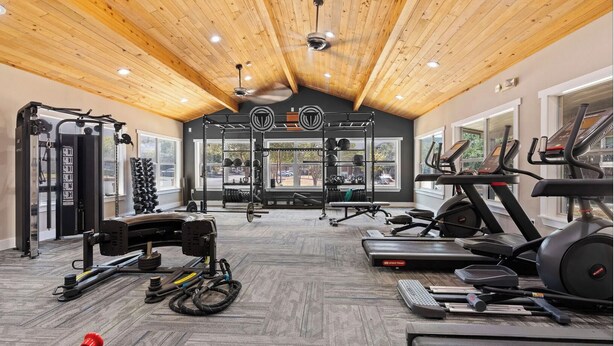Une salle de sport équipée de divers appareils d’exercice, notamment des tapis de course, des appareils de musculation et des poids libres.
