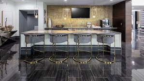 A modern kitchen with a central island, bar stools, and a flat-screen TV mounted on the wall. - Landing | Incredible 2BD, Gym (Houston)