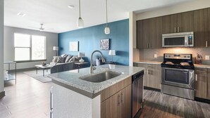 A modern kitchen with granite countertops, stainless steel appliances, and wooden cabinets. - Landing | Incredible 2BD, Gym (Houston)