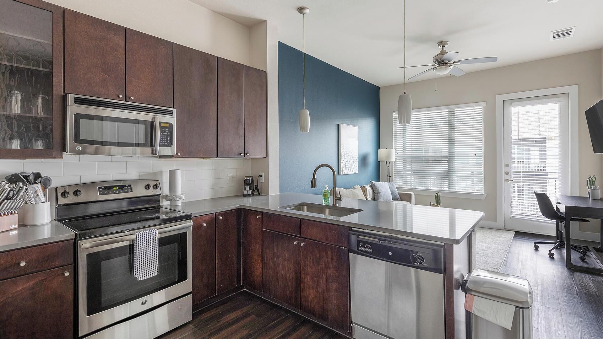 Una cocina moderna con armarios de madera oscura, electrodomésticos de acero inoxidable y una pared de acento azul.