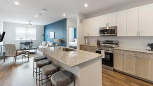 A modern kitchen with a granite countertop, stainless steel appliances, and wooden cabinets.