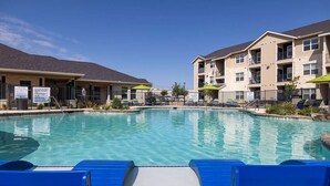 Une piscine avec des chaises longues bleues et un ciel d’un bleu limpide.